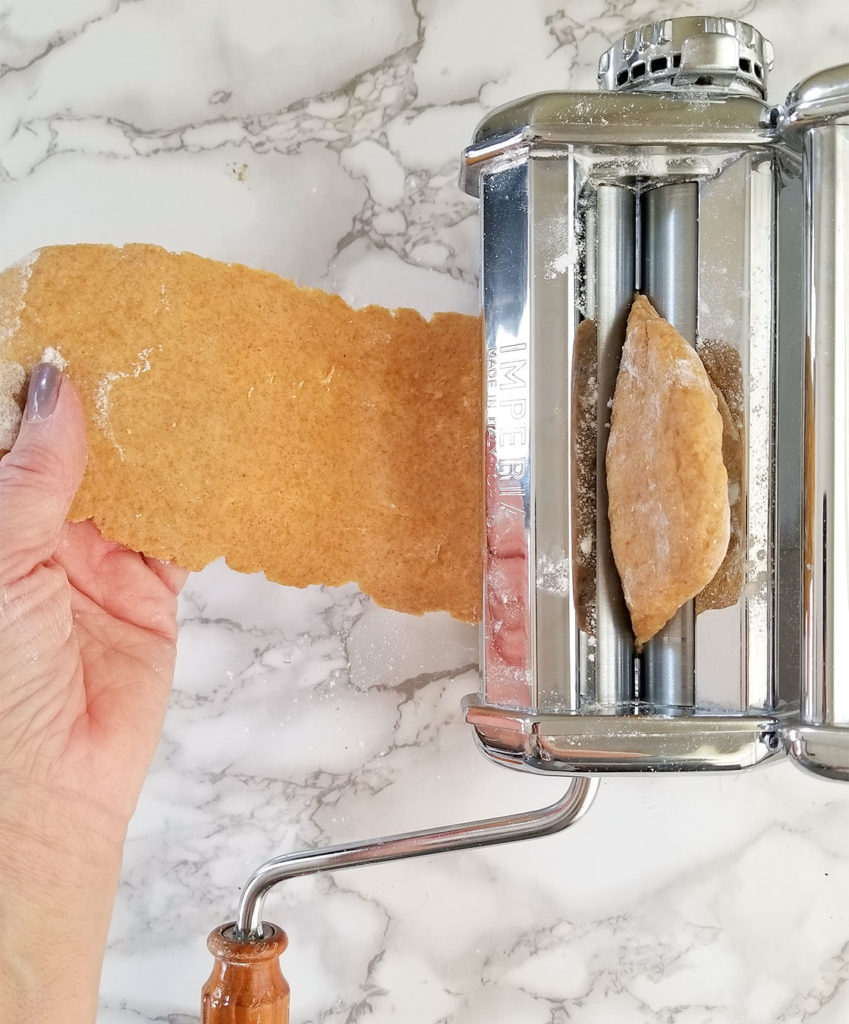 Homemade Wheat Pasta dough rolling through a pasta machine