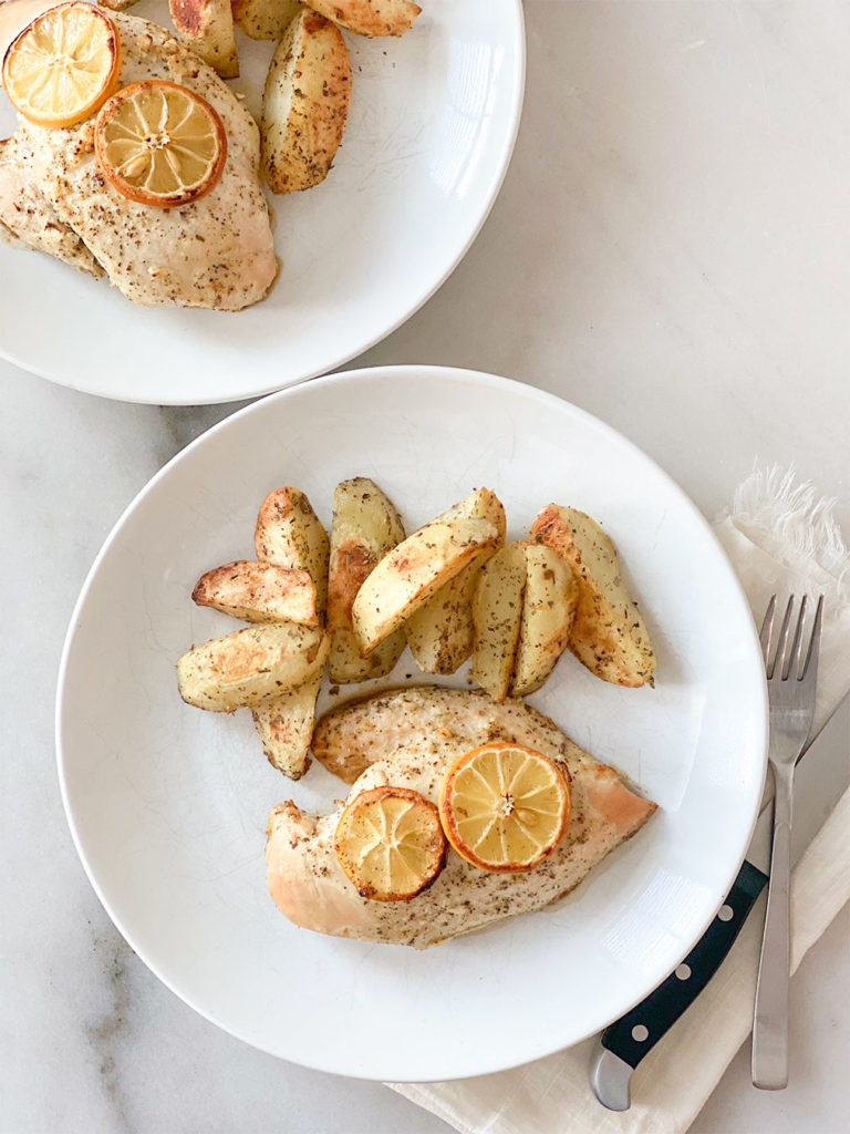 Cooked lemon chicken breasts on a plate served with greek lemon potatoes